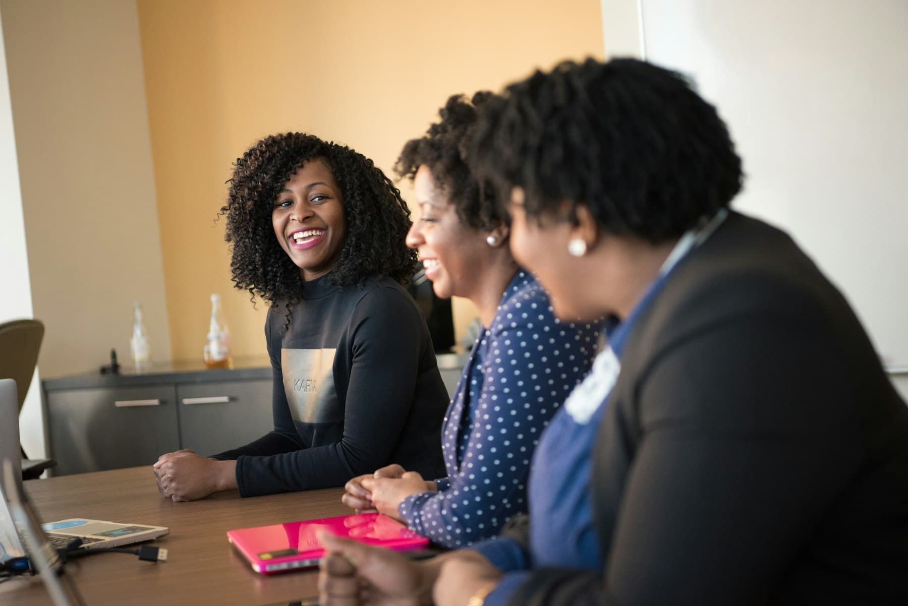 Three women leaders laughing together in a meeting